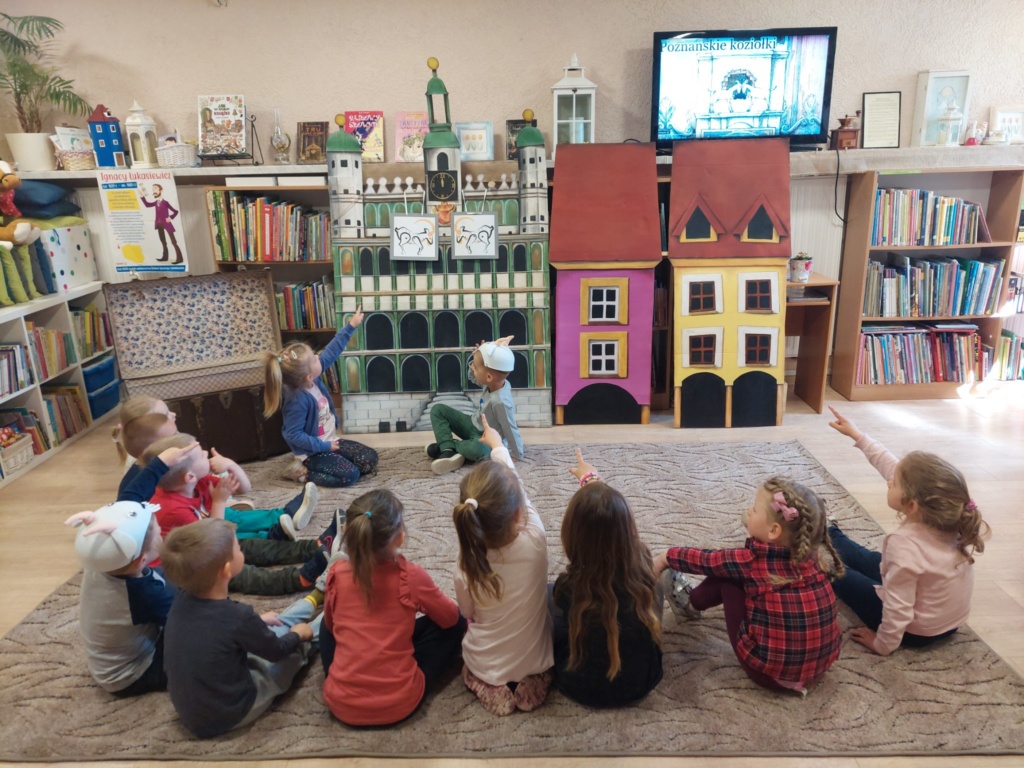 Dzieci siedzą na dywanie i oglądają film na dużym ekranie